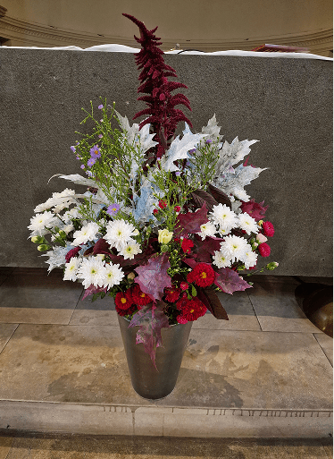 Composition florale majestueuse avec amarante pourpre, fleurs blanches et feuillages argentés dans un vase sombre.