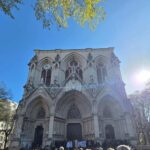 Rassemblement de fidèles devant l'entrée de l'église de la Rédemption sous un ciel ensoleillé.